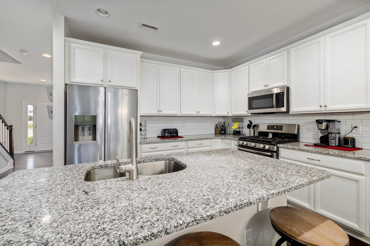 Spacious kitchen featuring granite countertops, white cabinets, and stainless steel appliances.