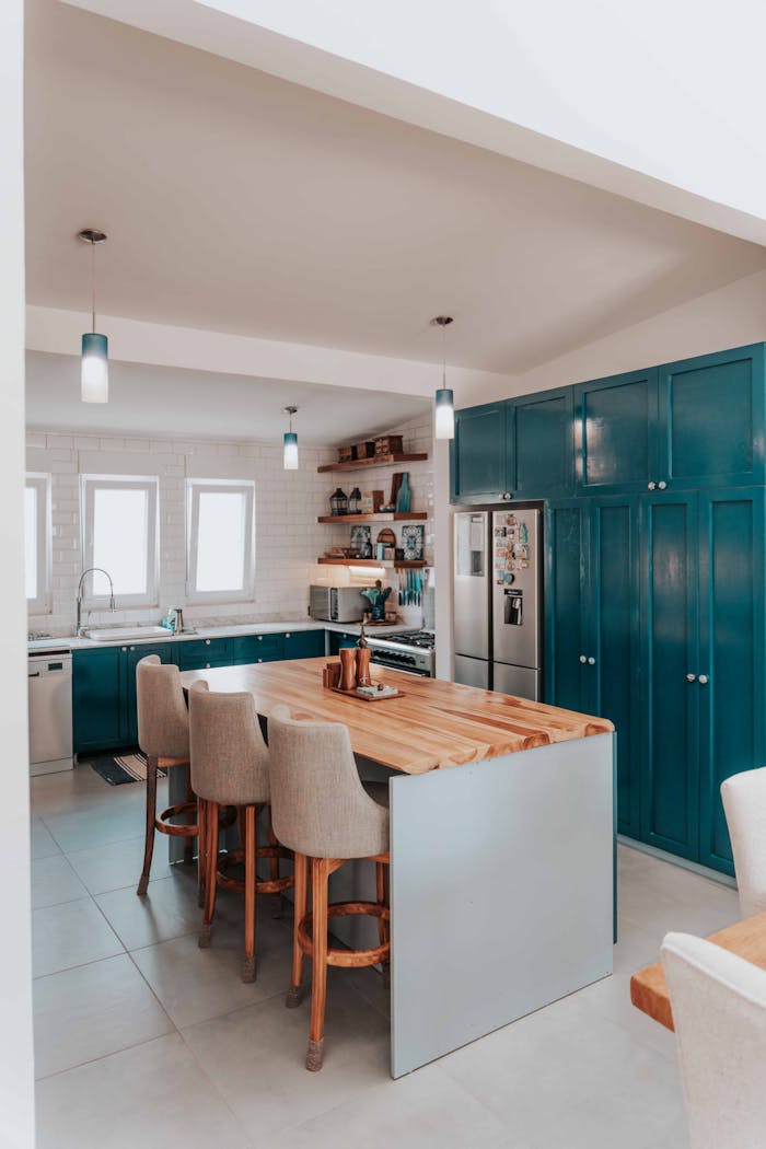 A stylish kitchen featuring blue cabinets, wood countertops, and bar stools.